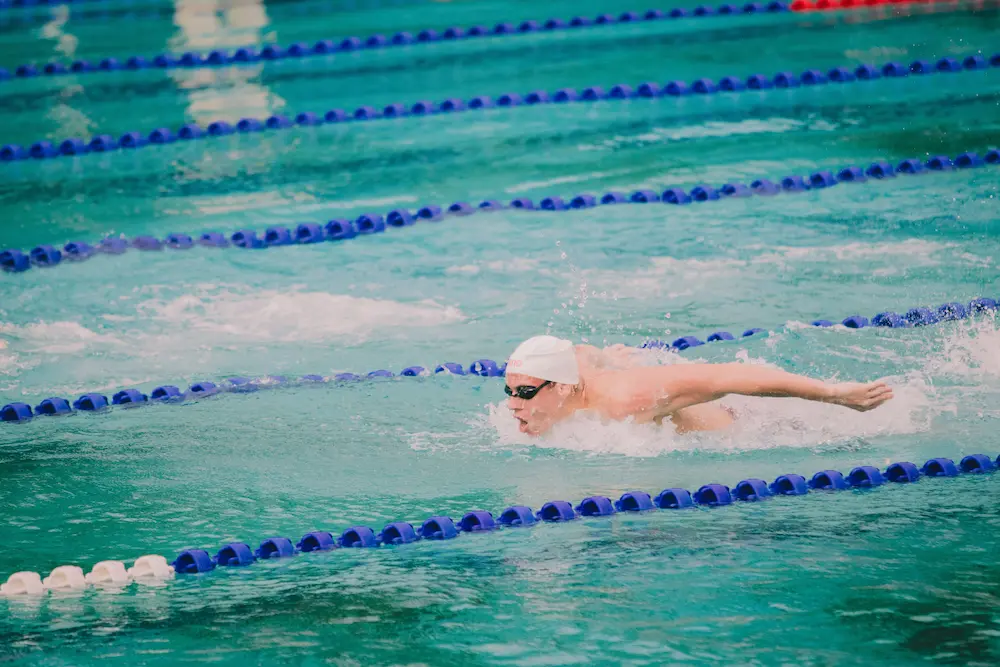 Club swimmer in a white cap fighting through a butterfly stroke at race pace