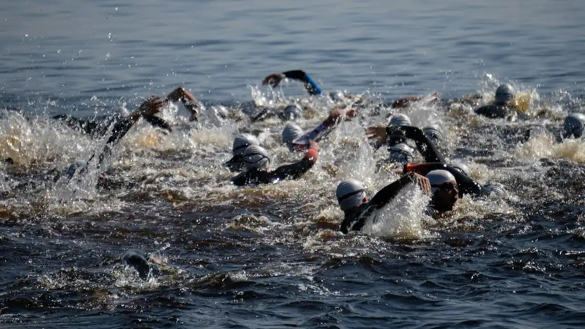 Open-water triathlon mass start with swimmers churning the water